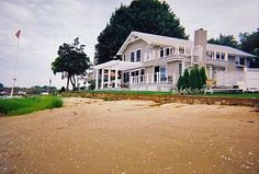 a large white house sitting on top of a sandy beach