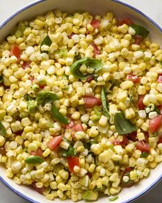 a bowl filled with corn and garnish on top of a table