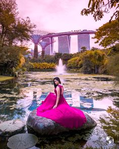 a woman in a pink dress sitting on top of a rock