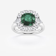 an emerald and diamond ring with two halos on the shoulders, set in white gold