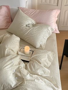 a bed with two pillows and a candle on it