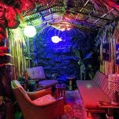 a living room filled with lots of furniture and lights on the ceiling next to a stone wall