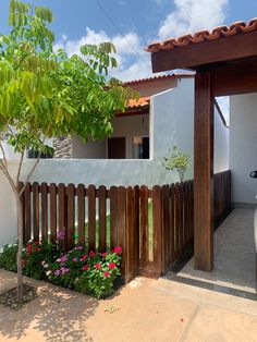 a car parked in front of a house with a wooden fence and flowers growing on the ground