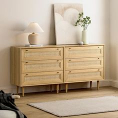 a room with a white rug and a wooden dresser next to a lamp on the wall