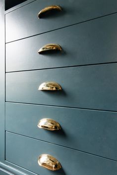 a blue dresser with brass handles and knobs