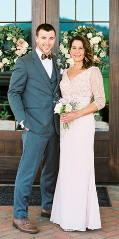 a man and woman standing next to each other in front of a door with flowers