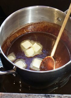 a pot filled with ice cubes sitting on top of a stove next to a wooden spoon