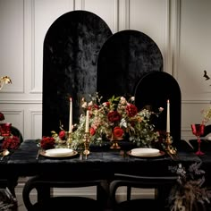 a black table topped with plates and candles