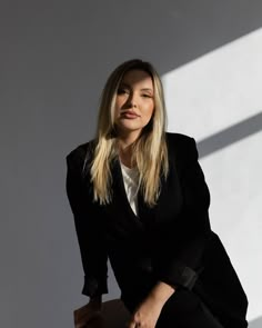 a woman in a black suit sitting on a chair