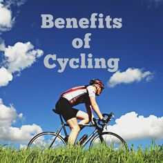 a man riding a bike on top of a lush green field under a blue sky