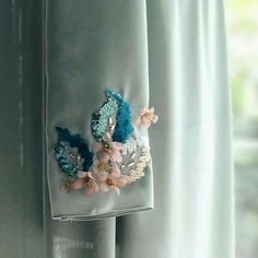 a close up of a piece of cloth with flowers on it hanging from a curtain