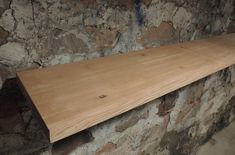 a wooden shelf sitting on top of a stone wall