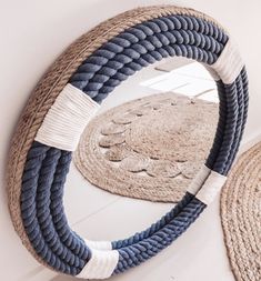 a round mirror sitting on top of a wall next to a rope doormat and rug