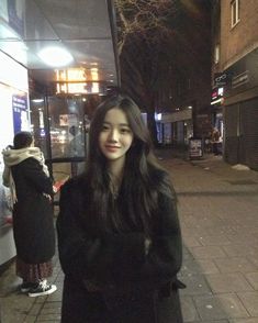 a woman standing on the sidewalk in front of a store