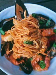 a plate with spaghetti and mussels on it, being held by a fork