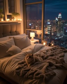 a cat laying on top of a bed next to a window with candles in it