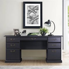 a black desk with two drawers and a framed photograph on the wall next to it