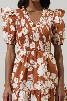 The dress for your next brunch date is our lovely Surrey Floral Leones Smocked Mini Dress. A white floral print sits on brown background with cotton fabric. Features a ruffle trim V neckline and fully smocked bodice framed by short puff sleeves. It tops a flared ruffle tier mini skirt. Wear it white loafers and gold accessories. - Breathable- Smocked bodice- Ruffle details- Pockets- Color: Rust CreamSize + Fit - Model is 5'9" and wearing size XS- Measurements taken from size S - Chest: 14 1/2"- Brown Smocked Bodice Dress For Brunch, Brown Cotton Floral Print Dress, Brown Smocked Back Dress For Brunch, Brown Dresses With Smocked Back For Brunch, Brown Dress With Smocked Back For Brunch, Brown Floral Print Puff Sleeve Dress, Brown Puff Sleeve Floral Print Dresses, Smocked Mini Dress, White Loafers