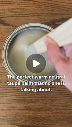 a person holding a paintbrush in front of a can with the words, the perfect warm neutral tape painted that no one is talking about