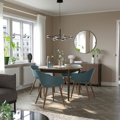 a dining room table with four chairs and a round mirror on the wall above it