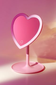 a pink heart shaped light on a stand in the middle of a room with clouds