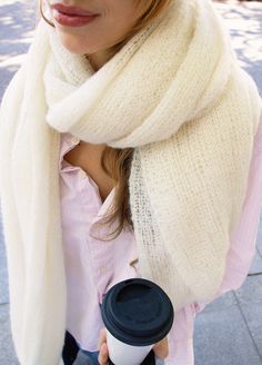 a woman is holding a coffee cup and scarf