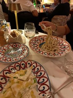 the table is set with plates of food and wine glasses