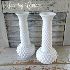 two white vases sitting on top of a wooden table next to each other and the words monday cottage above them