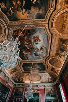 a chandelier hanging from the ceiling in a room with paintings on the walls