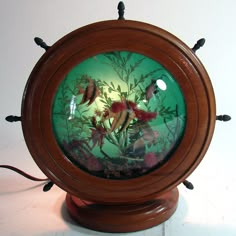 an aquarium with fish and plants in it on a wooden stand next to a white wall