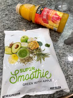 a bag of green smoothie sitting on top of a counter next to a bottle of juice