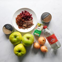 an assortment of fruits, nuts and spices on a white counter top next to a bottle of water