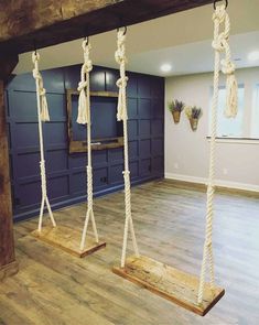 a room with wooden floors and ropes hanging from the ceiling in front of a blue wall