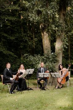 four people are playing music in the park