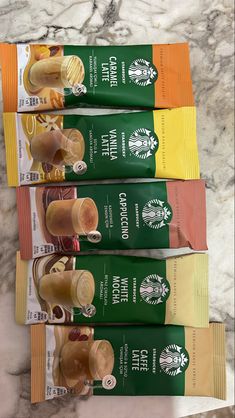 four starbucks coffee packets lined up next to each other on a marble counter top,