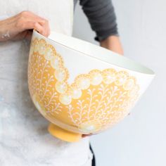 a woman is holding a yellow and white bowl