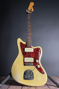 an old yellow guitar sitting on top of a wooden table next to a microphone and headphones