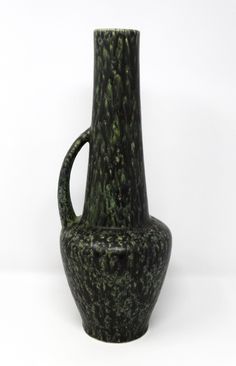 a green vase sitting on top of a white table