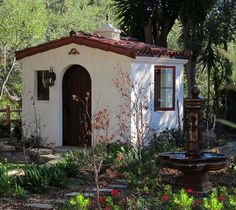 a small white building with a fountain in front of it