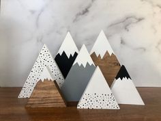 three wooden mountains with dots on them sitting on top of a wood table next to a marble wall