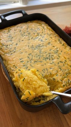 a casserole dish with eggs and herbs in it on a wooden table next to a fork