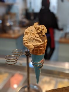 an ice cream cone with chocolate chunks in it on a stand at a bakery counter