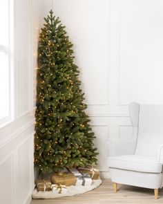 a small christmas tree next to a white chair