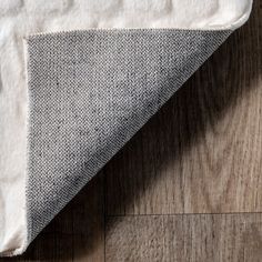 a close up view of a white and grey rug on a wood flooring surface