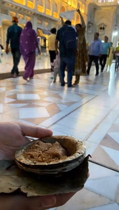 a person holding food in their hand while walking through a building with many other people