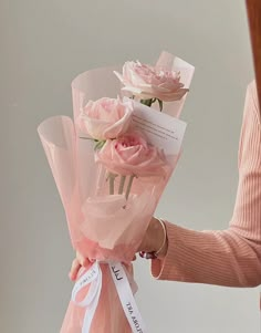 a woman is holding some pink roses in her hand