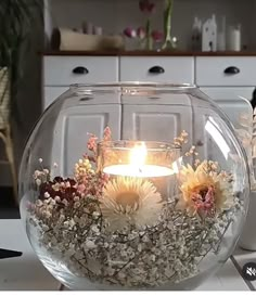 a glass bowl filled with flowers and a lit candle