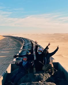 two people sitting in the back of a truck with their arms up and hands raised