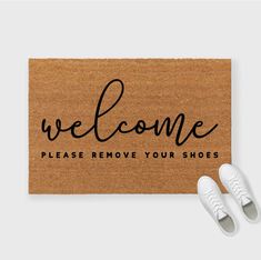 a pair of white shoes sitting on top of a door mat that says welcome please remove your shoes