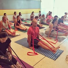 a group of people sitting on mats doing yoga with red straps around their ankless